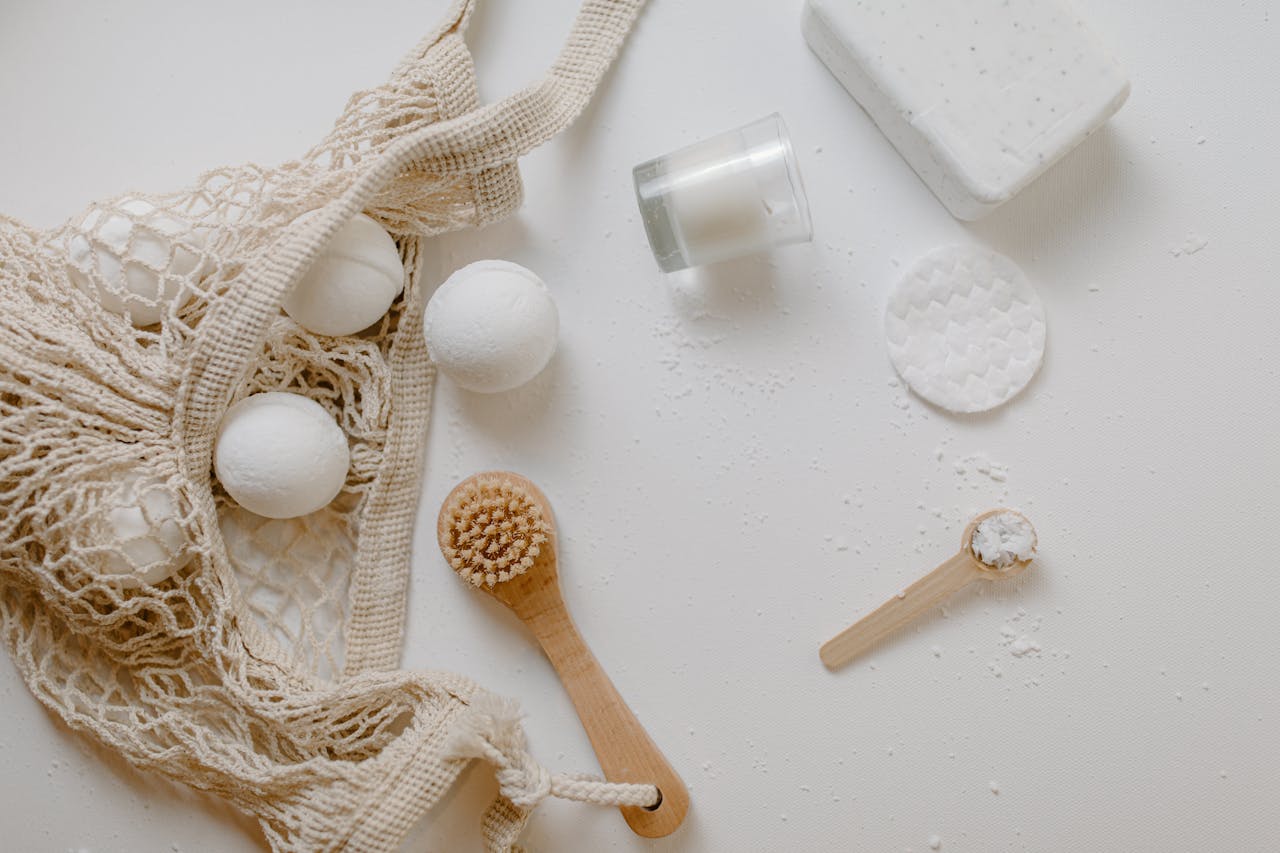 Minimalist flat lay of eco-friendly bath essentials including bath bombs, soap, and a brush.